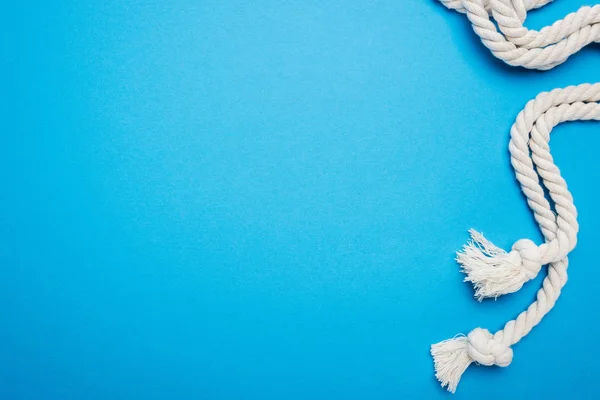 Cordas brancas e longas com nós isolados em azul — Fotografia de Stock