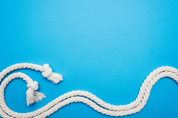 Cordas onduladas longas brancas com nós isolados em azul — Fotografia de Stock