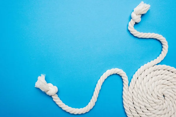 Twisted white ropes with knots isolated on blue — Stock Photo