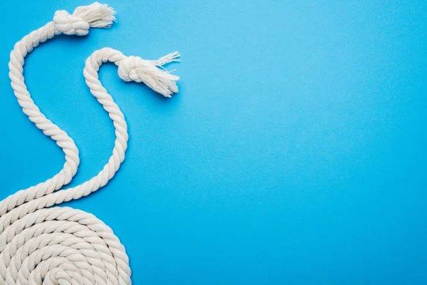 Cordes ondulées et torsadées blanches avec nœuds isolés sur bleu — Photo de stock