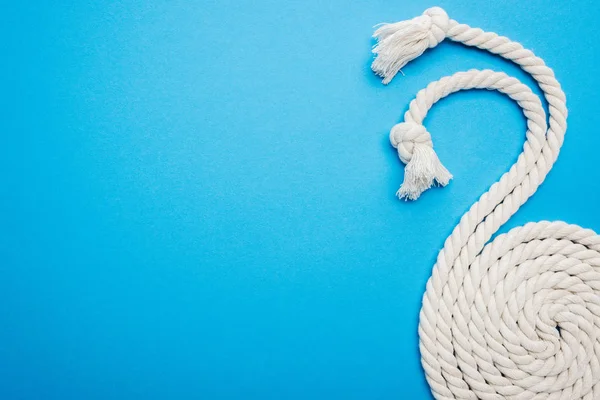 Longo branco ondulado e torcido cordas com nós isolados em azul — Fotografia de Stock