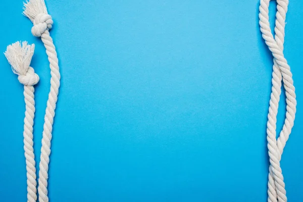 Cordas longas onduladas brancas com nós isolados em azul — Fotografia de Stock