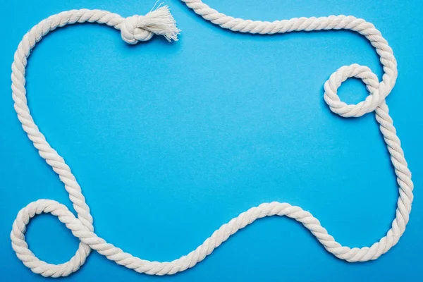 Top view of white waved long rope with knot isolated on blue — Stock Photo