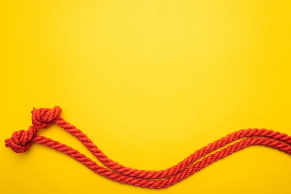 Red jute waved ropes with knots isolated on orange — Stock Photo