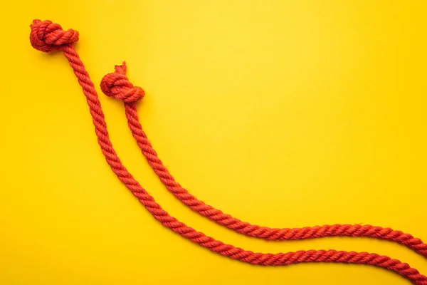 Jute rouge et cordes longues avec nœuds isolés sur orange — Photo de stock