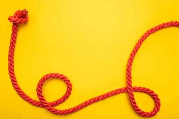 Red jute and curled ropes with knot isolated on orange — Stock Photo