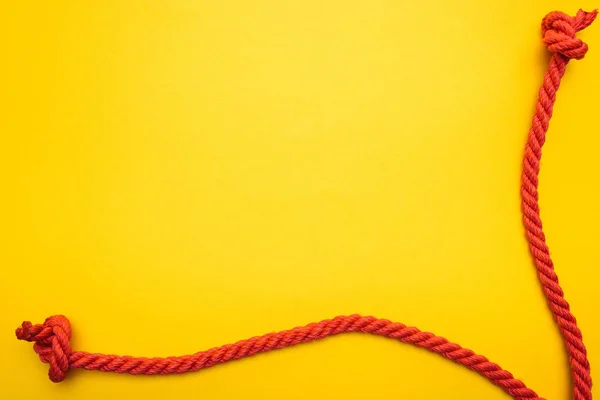 Red jute ropes with knots isolated on orange — Stock Photo