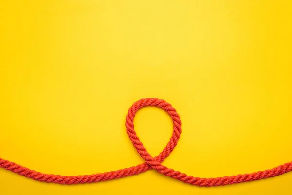 Red long and curled rope isolated on orange — Stock Photo