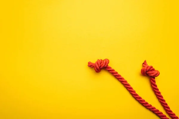 Cuerdas rojas y largas con nudos retorcidos aislados en naranja - foto de stock