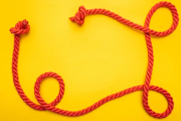 Curled and red rope with twisted knots isolated on orange — Stock Photo