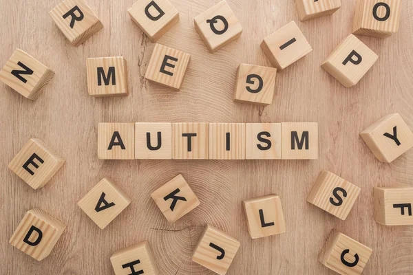 Top view of autism lettering made of wooden cubes with different letters on wooden table — Stock Photo