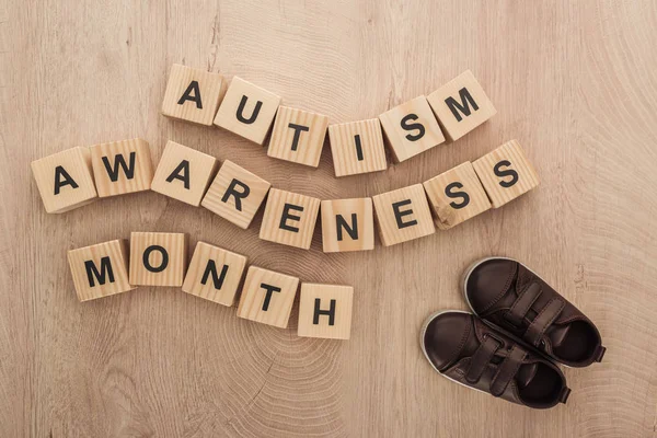 Vista superior de autismo conciencia mes palabras hechas de bloques de madera cerca de los niños zapatillas de deporte - foto de stock