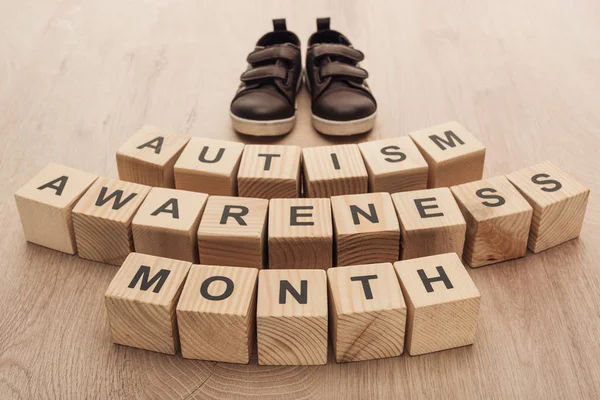 Mots mois de sensibilisation à l'autisme en blocs de bois près de baskets enfants marron — Photo de stock