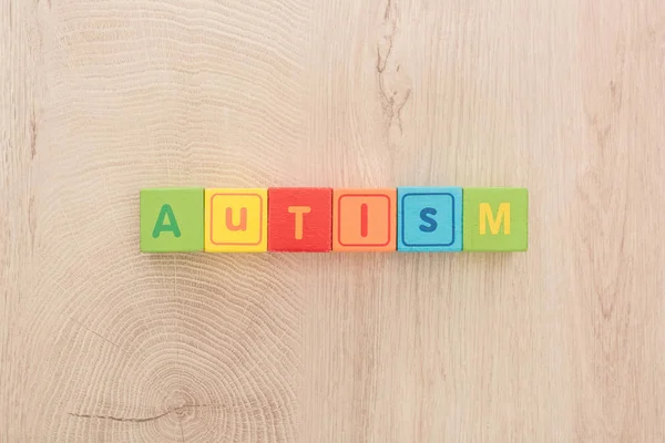Top view of autism lettering made of multicolored cubes on wooden table — Stock Photo