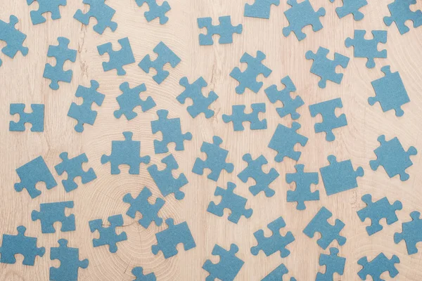 Draufsicht auf blaue Puzzleteile auf Holztisch verstreut — Stockfoto