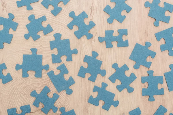 Draufsicht auf blaue Puzzleteile auf Holztisch verstreut — Stockfoto