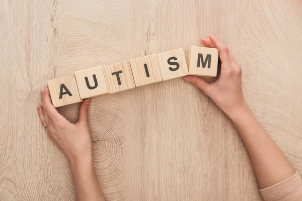 Cropped view of woman holding wooden cubes with autism lettering — Stock Photo