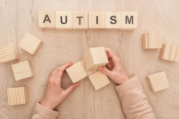 Vue recadrée de la femme tenant des cubes en bois vides avec espace de copie près de lettrage autisme — Photo de stock