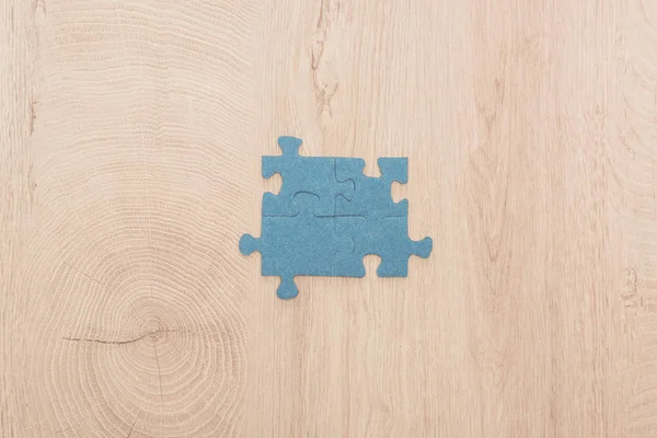Top view of blue puzzle pieces connected on wooden table — Stock Photo
