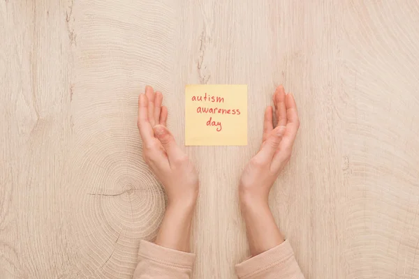 Частичный взгляд на женские руки и липкая нота с красной надписью в день осознания аутизма — стоковое фото