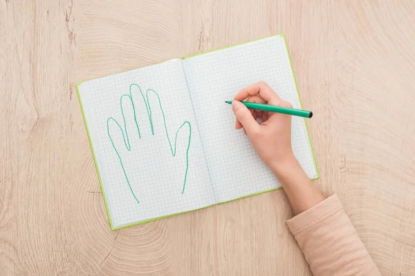 Vista recortada de la mano femenina en el cuaderno abierto cerca de la palma humana dibujada - foto de stock