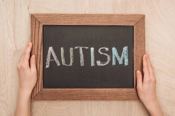 Cropped view of woman holding chalkboard with autism lettering — Stock Photo