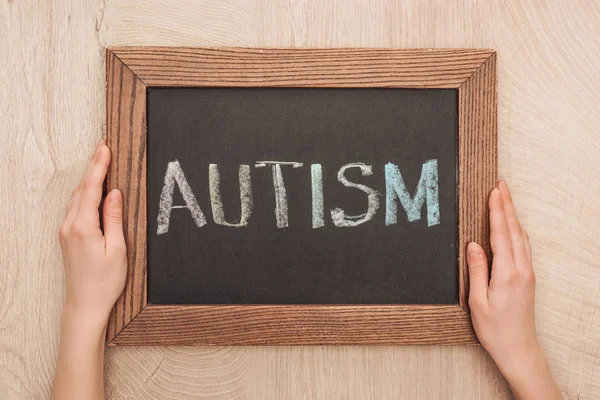 Vista cortada da mulher segurando quadro com letras autismo — Fotografia de Stock