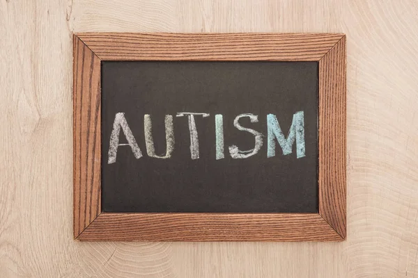 Верхний вид доски с надписью аутизма на деревянном столе — стоковое фото