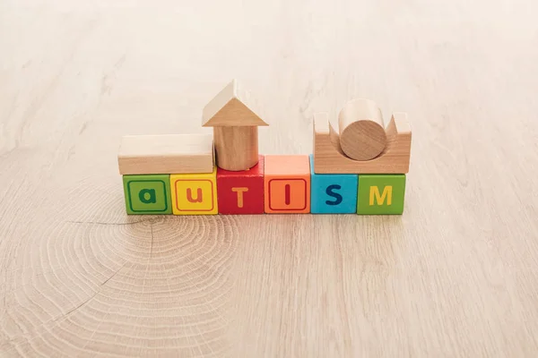 Autism lettering made of colorful cubes with building blocks on wooden surface — Stock Photo