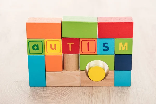 Autism lettering made of colorful building blocks on wooden surface — Stock Photo