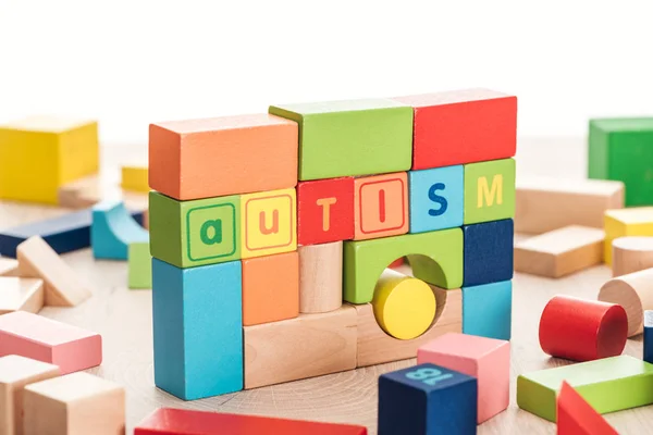 Lettering autistico fatto di blocchi di costruzione colorati su superficie di legno isolato su bianco — Foto stock