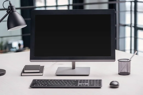 Monitor de ordenador con pantalla en blanco y papelería en el lugar de trabajo - foto de stock