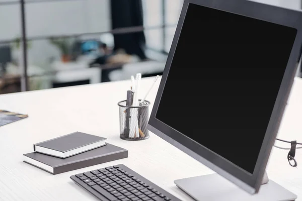 Primer plano del monitor de ordenador con pantalla en blanco y papelería en el lugar de trabajo - foto de stock