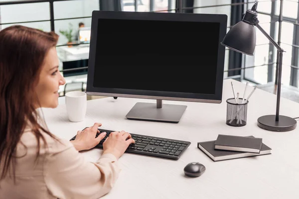 Selective focus of smiling woman using computer at workplace — Stock Photo