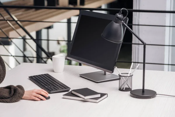 Partial view of woman using computer at workplace with stationery and cup — Stock Photo