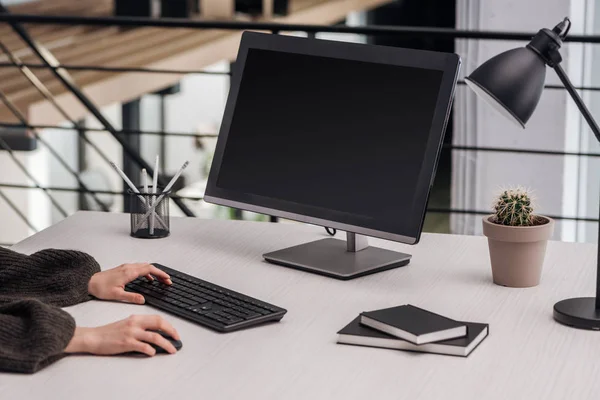 Cropped view of woman using computer at workplace with stationery — Stock Photo