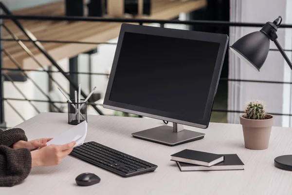 Cropped view of woman holding papers at workplace in modern office — Stock Photo