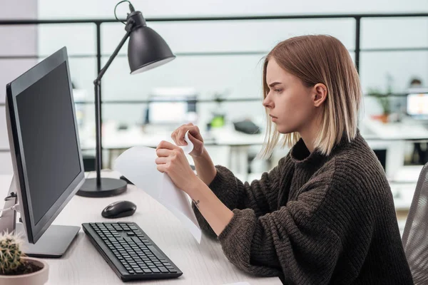 Sad girl tearing paper at workplace in modern office — Stock Photo