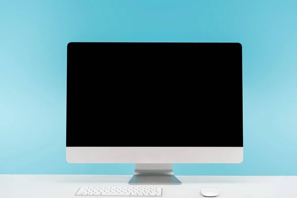 Local de trabalho com monitor de computador, teclado e mouse de computador na mesa branca no fundo azul — Fotografia de Stock