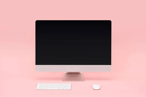 Робоче місце з монітором комп'ютера, клавіатурою та комп'ютерною мишею на рожевому фоні — стокове фото