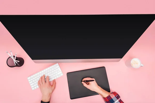 Обрезанный вид человека с помощью компьютера и графического планшета на розовом фоне — стоковое фото
