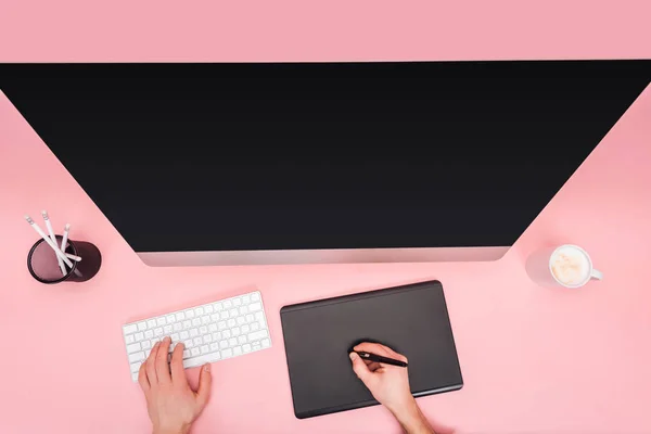 Partial view of man using computer and graphic tablet on pink background — Stock Photo