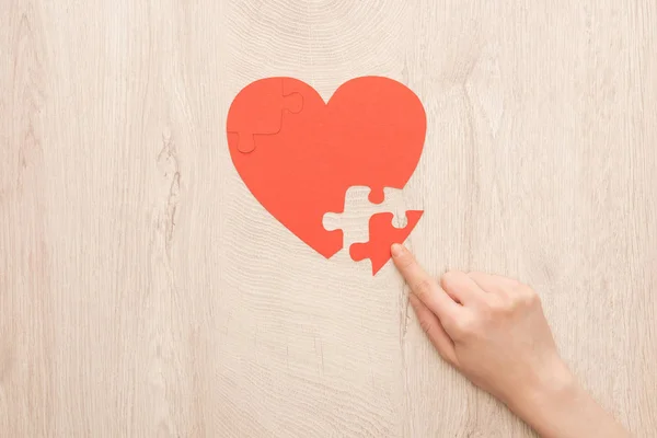 Cropped view of woman pointing with finger to puzzle of heart — Stock Photo