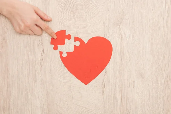 Partial view of woman pointing with finger to puzzle of heart — Stock Photo