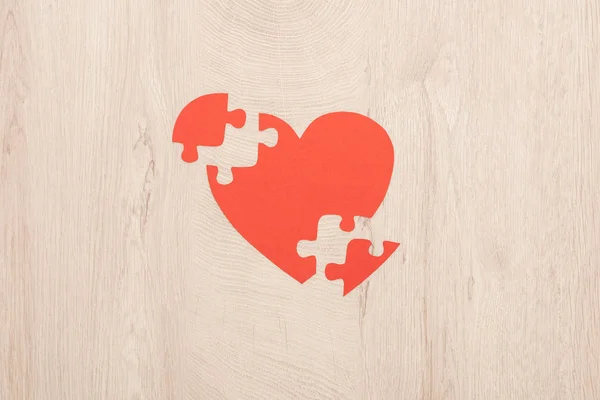 Top view of bright paper heart and pieces of puzzle on wooden background — Stock Photo