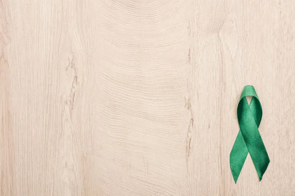 Top view of green ribbon on wooden background with copy space — Stock Photo