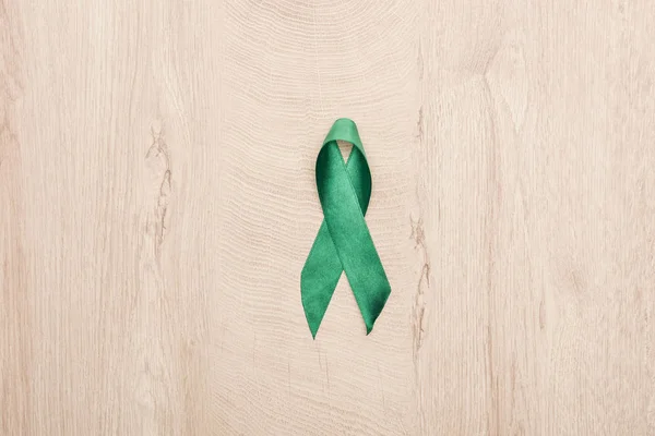 Top view of green ribbon on wooden background with copy space — Stock Photo