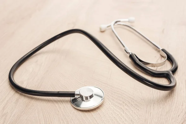 Selective focus of stethoscope on wooden and white table — Stock Photo