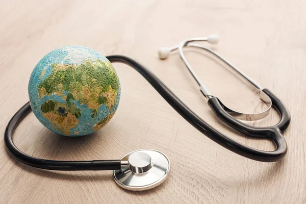 Selective focus of stethoscope and toy earth on wooden and white table — Stock Photo