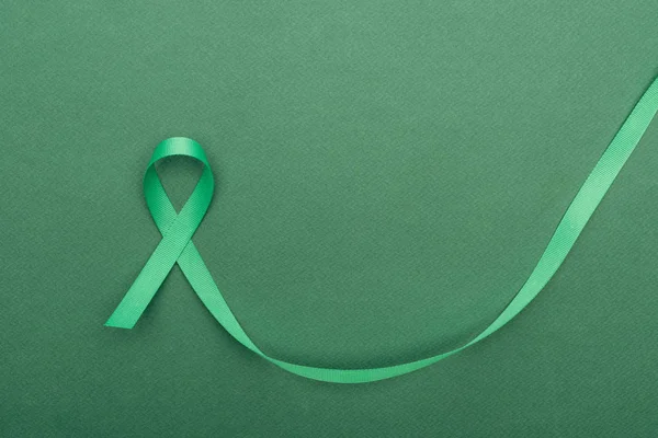 Top view of green and colorful ribbon on green background with copy space — Stock Photo